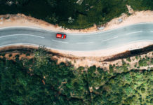 Aerial view on red car on the road near tea plantation