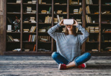 Happy woman wearing VR Glasses in front of bookshelves